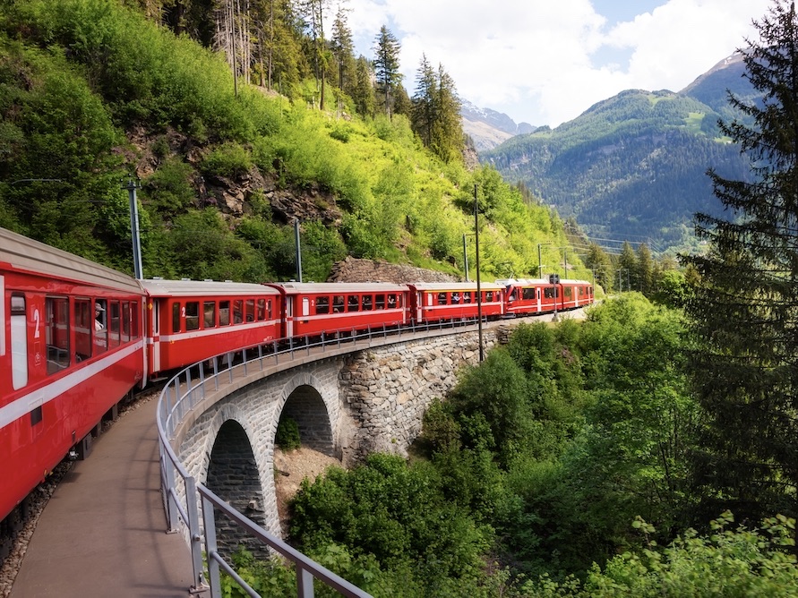 Red train moving in beautiful mountain landscape from Tirano (Valtellina, Italy) to Switzerland
