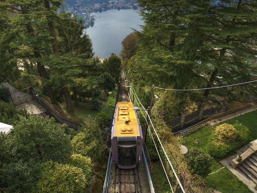 Funicular in motion going up the heal with Como Lake in the background.
